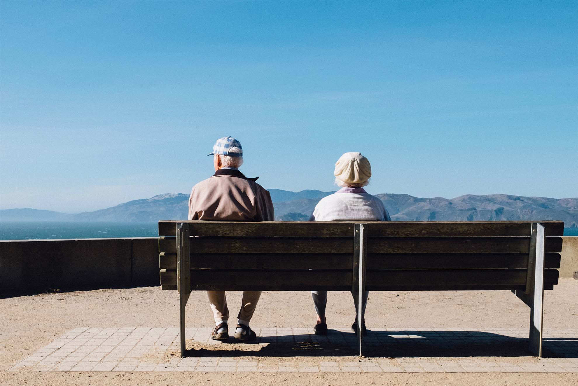 Two elderly people sat on a bench