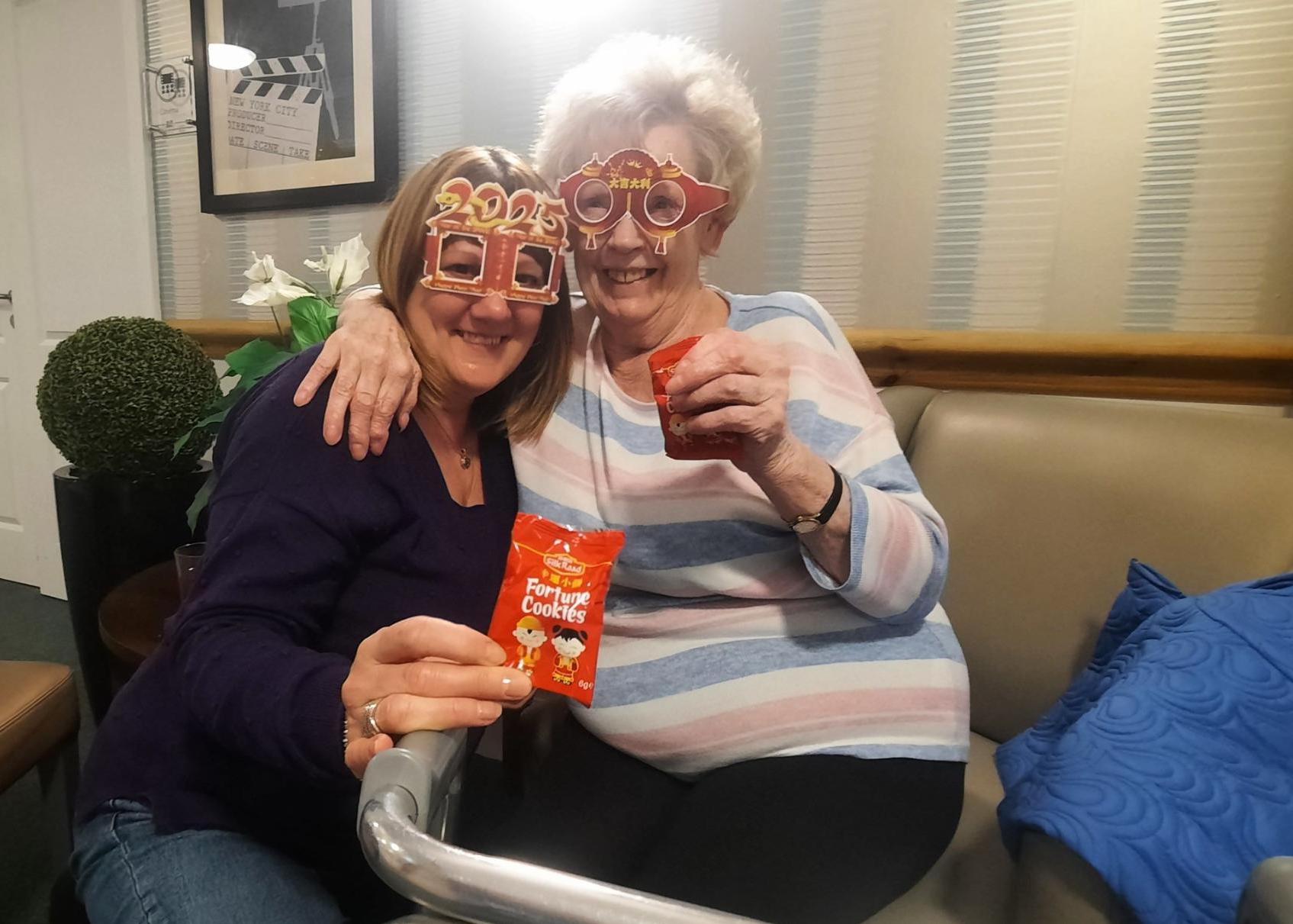 residents sat with a loved one with fortune cookies in hand celebrating chinese new year