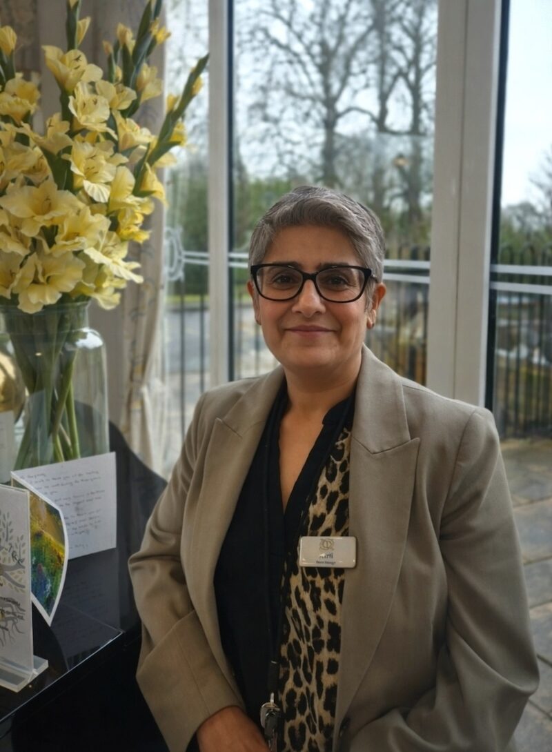 Woman wearing a grey suit smiling having her headshot taken for the team page