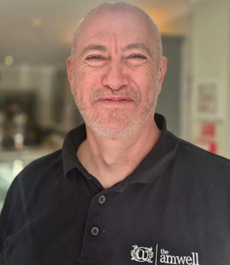 Man in a black maintenance uniform having a headshot taken for the team page