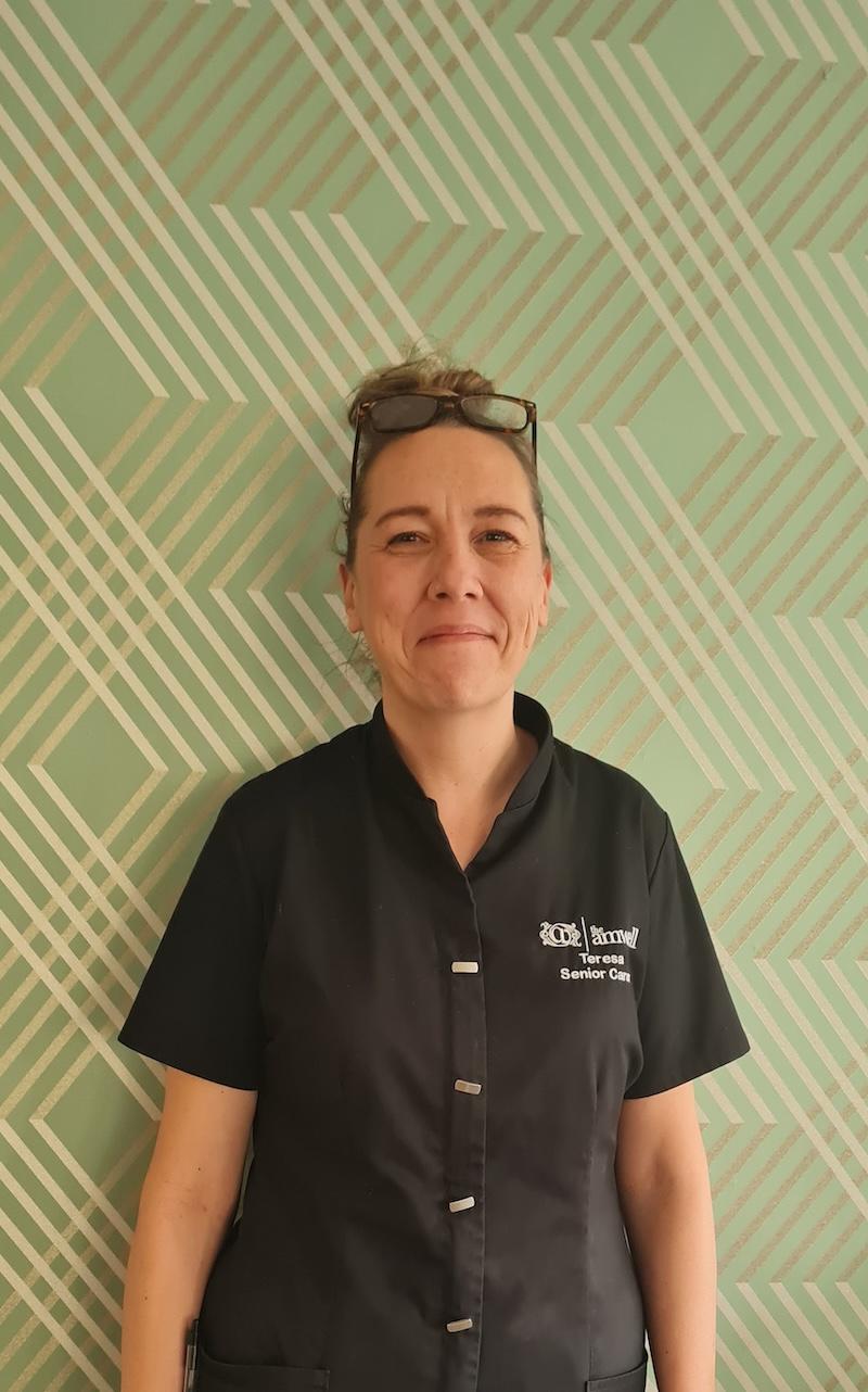 Woman with her hair tied up in a black team leader uniform having a headshot taken for the team page
