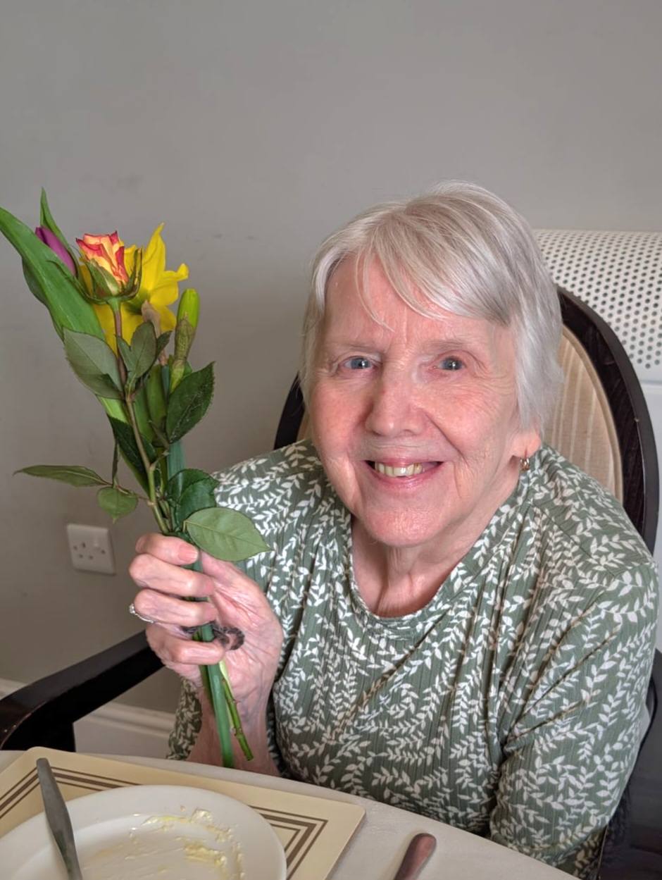 older lady holding a flower
