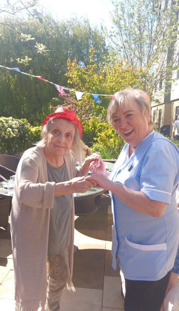 a resident and carer stood dancing together